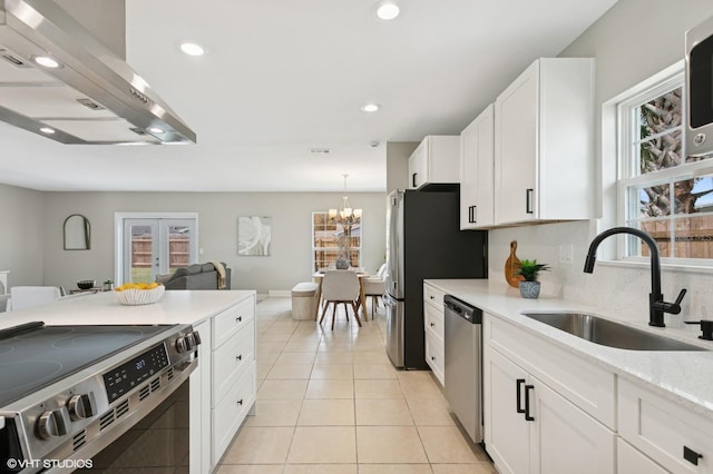 kitchen featuring light tile patterned floors, exhaust hood, white cabinets, stainless steel appliances, and a sink