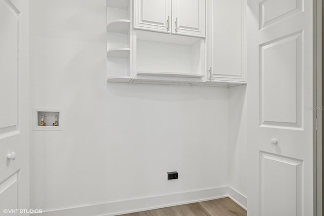 clothes washing area with cabinet space, wood finished floors, baseboards, and washer hookup