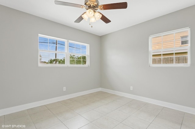 spare room with light tile patterned flooring, a ceiling fan, and baseboards