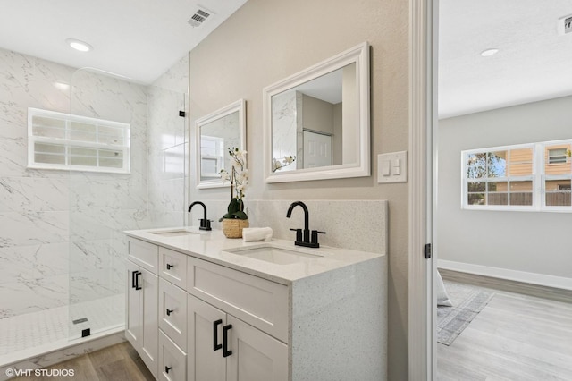 bathroom with a sink, visible vents, wood finished floors, and a walk in shower