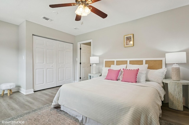 bedroom featuring a ceiling fan, wood finished floors, visible vents, baseboards, and a closet