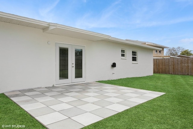 rear view of house featuring fence, stucco siding, french doors, a yard, and a patio