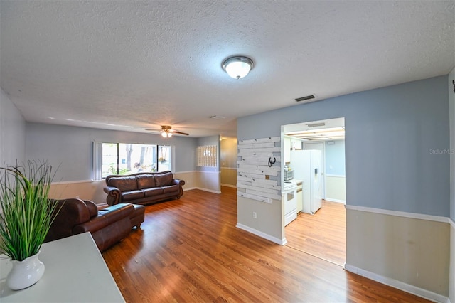 living room with visible vents, a textured ceiling, and light wood-style floors