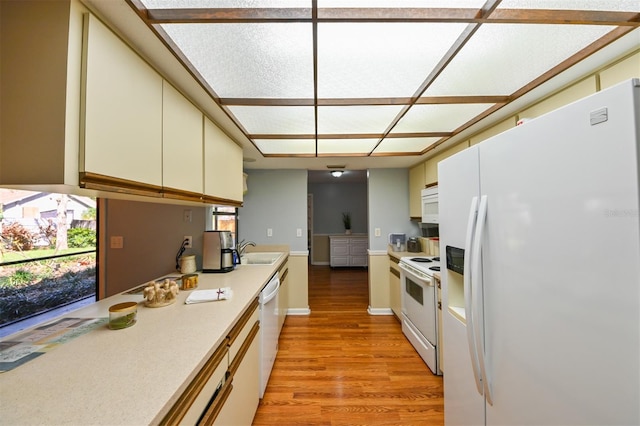 kitchen with white appliances, light wood-type flooring, light countertops, and a sink