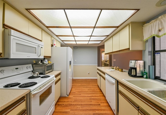 kitchen with white appliances, cream cabinetry, light wood-style flooring, and light countertops