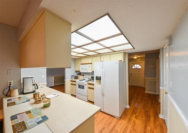 kitchen featuring light wood finished floors, white appliances, and light countertops