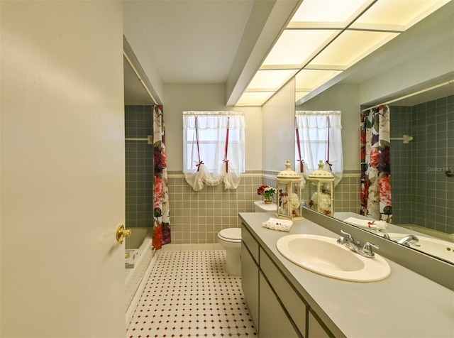 bathroom with toilet, tile walls, plenty of natural light, and vanity