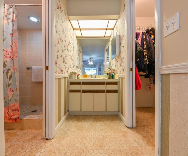 bathroom with a tile shower and vanity