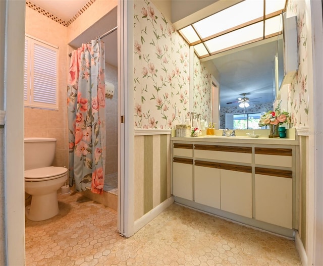 bathroom featuring wallpapered walls, toilet, a shower with shower curtain, a skylight, and vanity