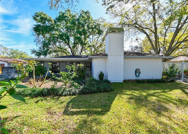 back of house with a lawn, fence, and a chimney