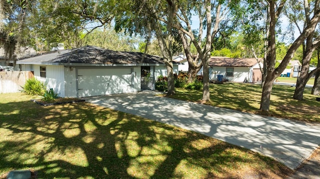 ranch-style home featuring driveway, an attached garage, and a front yard