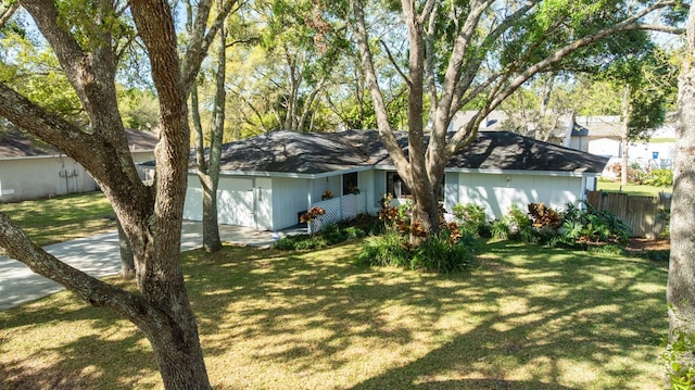 back of house with a lawn, concrete driveway, a garage, and fence