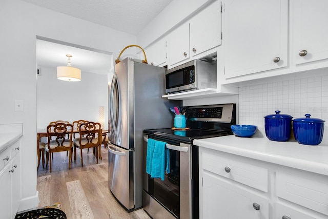 kitchen with backsplash, light wood-type flooring, light countertops, white cabinets, and stainless steel appliances