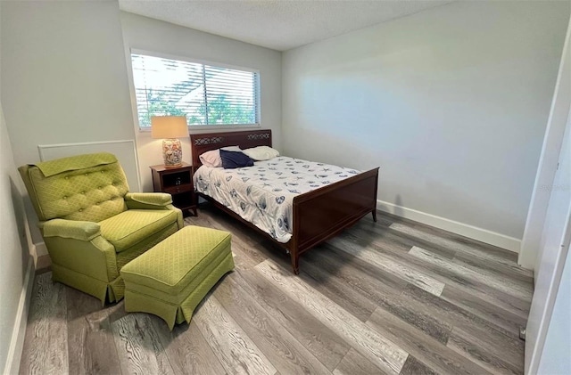 bedroom featuring wood finished floors, baseboards, and a textured ceiling