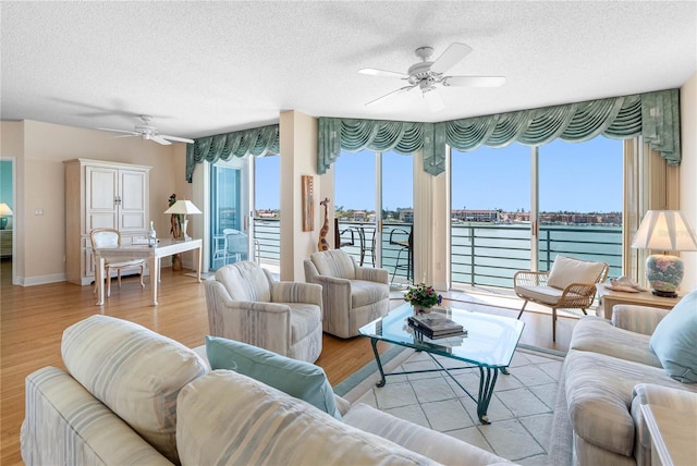 living room featuring a textured ceiling, plenty of natural light, wood finished floors, and ceiling fan