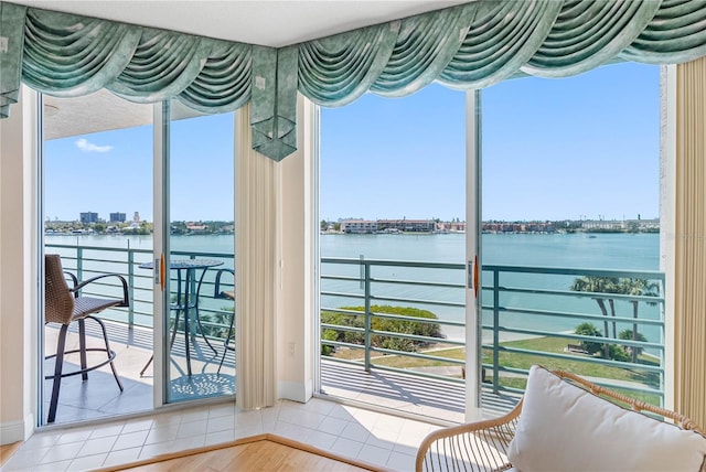 unfurnished sunroom with plenty of natural light, a view of city, and a water view