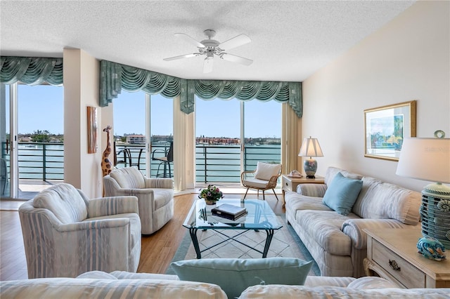 living room with a wealth of natural light, wood finished floors, and a ceiling fan