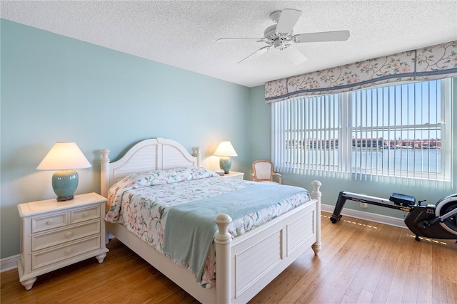 bedroom featuring baseboards, a textured ceiling, and wood finished floors