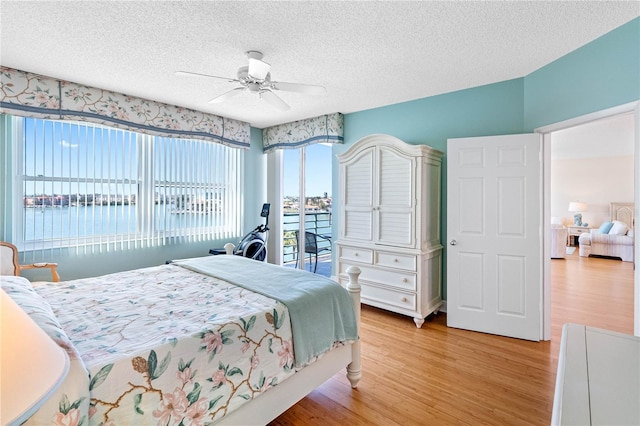 bedroom with ceiling fan, light wood finished floors, and a textured ceiling