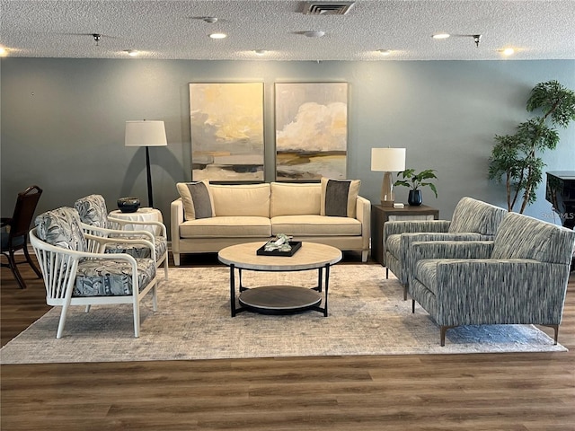 living area featuring wood finished floors, visible vents, and a textured ceiling