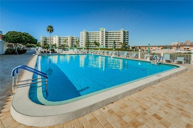 pool with a patio, a city view, and fence