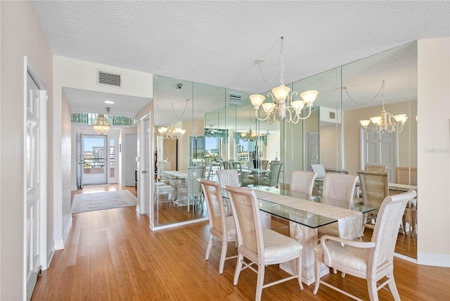 dining space featuring wood finished floors, visible vents, and a chandelier