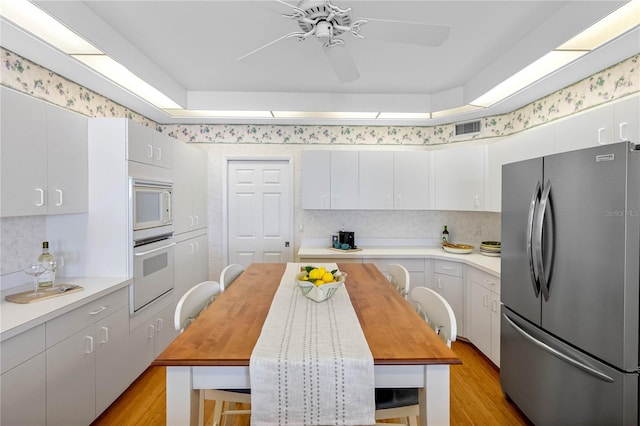 kitchen with visible vents, ceiling fan, butcher block counters, white appliances, and white cabinetry