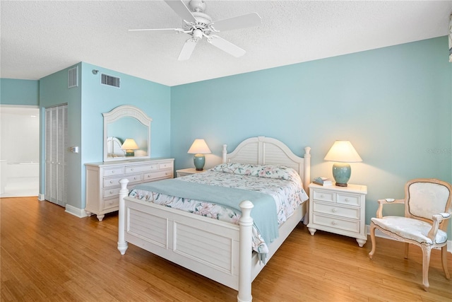 bedroom featuring visible vents, light wood finished floors, and a textured ceiling