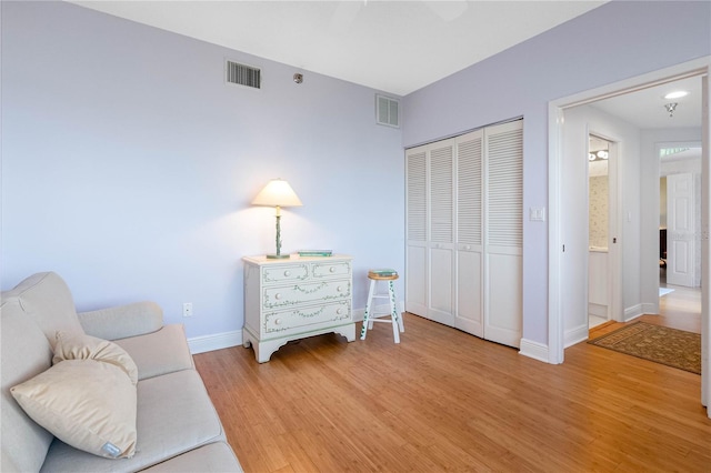 sitting room featuring light wood-style flooring, baseboards, visible vents, and ceiling fan