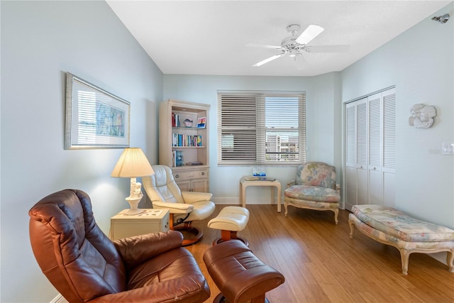 living area featuring wood finished floors, baseboards, and ceiling fan