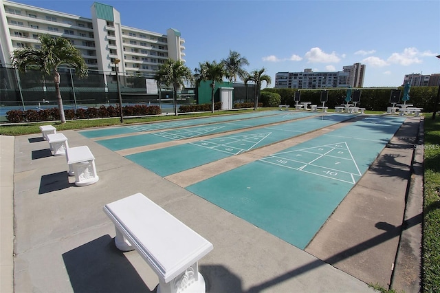 view of property's community with a view of city, shuffleboard, and fence