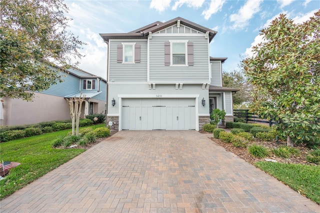 craftsman inspired home featuring decorative driveway, stone siding, fence, board and batten siding, and an attached garage