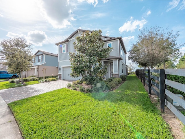 view of front facade featuring decorative driveway, a garage, a front lawn, and fence