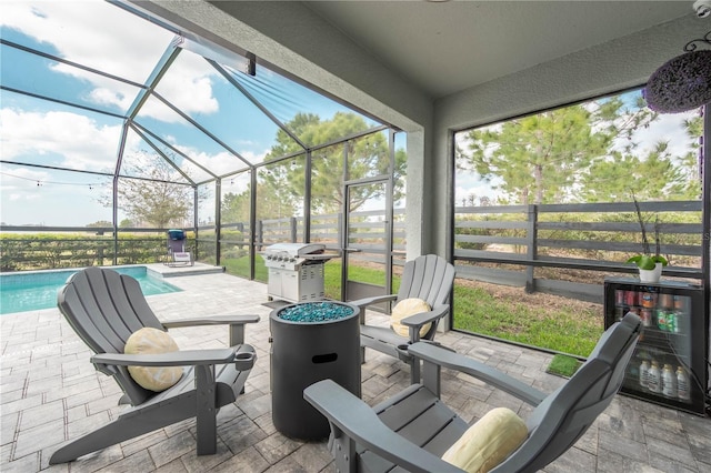 view of patio with fence, beverage cooler, an outdoor pool, a lanai, and a grill