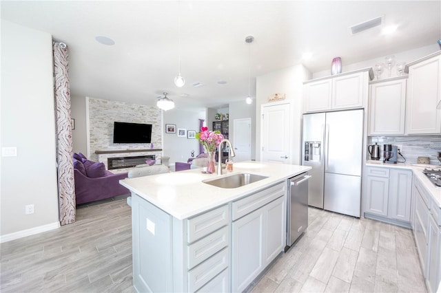 kitchen featuring light countertops, visible vents, stainless steel appliances, a sink, and open floor plan