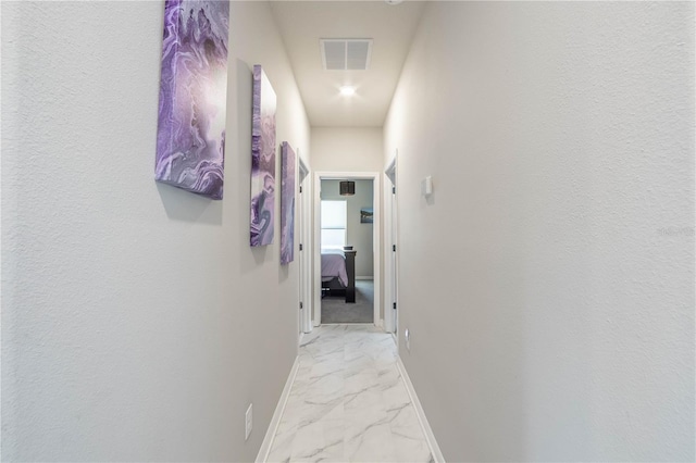 hallway featuring marble finish floor, baseboards, and visible vents
