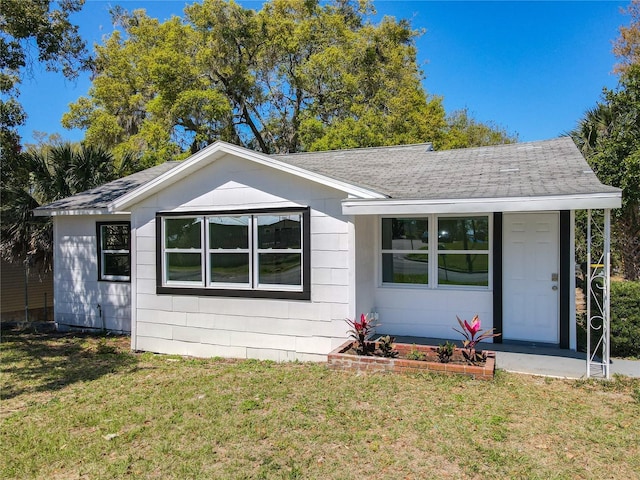 ranch-style home with a front lawn and roof with shingles