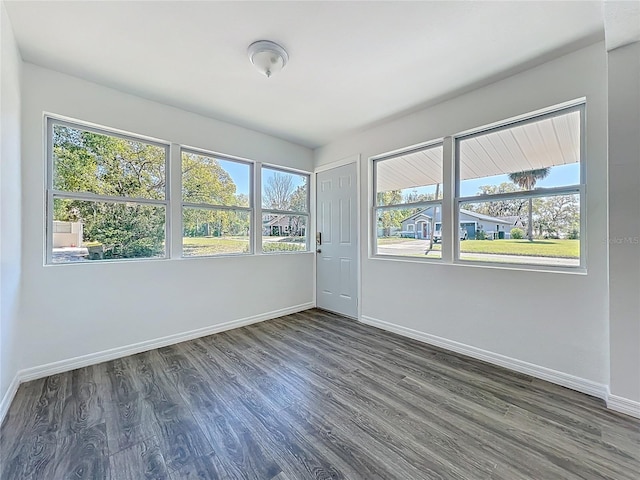 spare room with baseboards and dark wood-style flooring