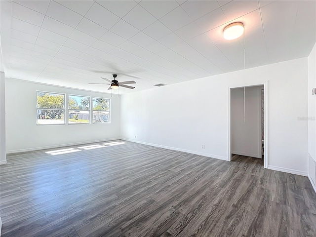 empty room with visible vents, baseboards, dark wood-type flooring, and a ceiling fan