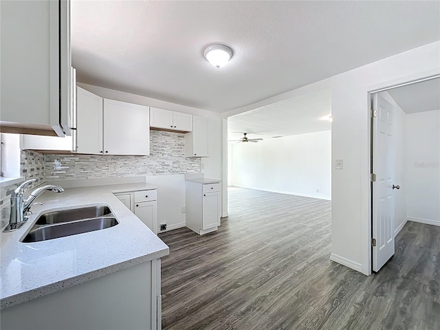 kitchen featuring a sink, light stone counters, ceiling fan, and dark wood-style flooring