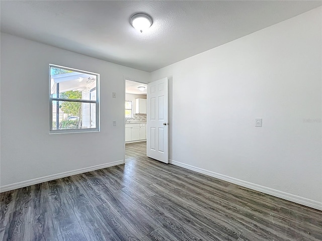 unfurnished room with dark wood finished floors and baseboards