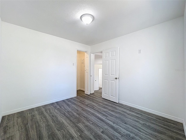 spare room featuring dark wood finished floors and baseboards