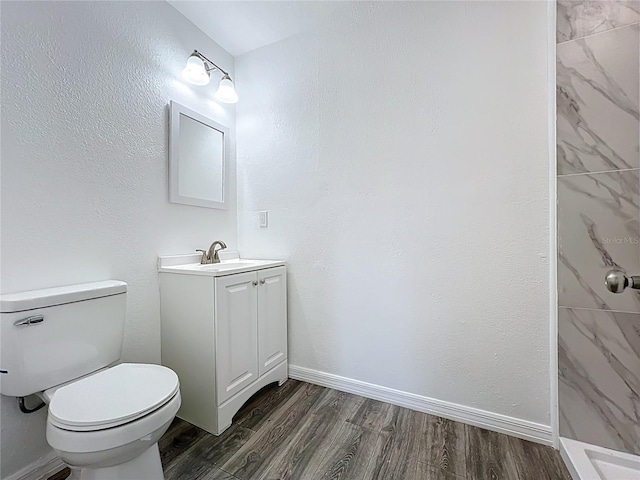 bathroom with toilet, vanity, baseboards, and wood finished floors