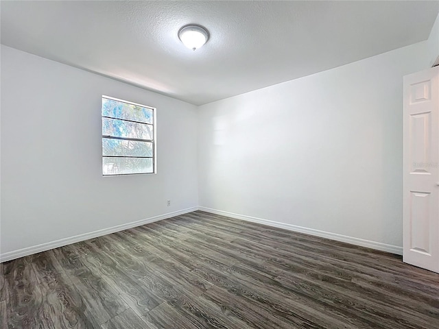 empty room with baseboards, dark wood-type flooring, and a textured ceiling