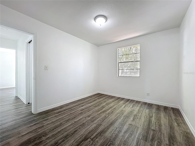 empty room with dark wood-style floors, baseboards, and a textured ceiling