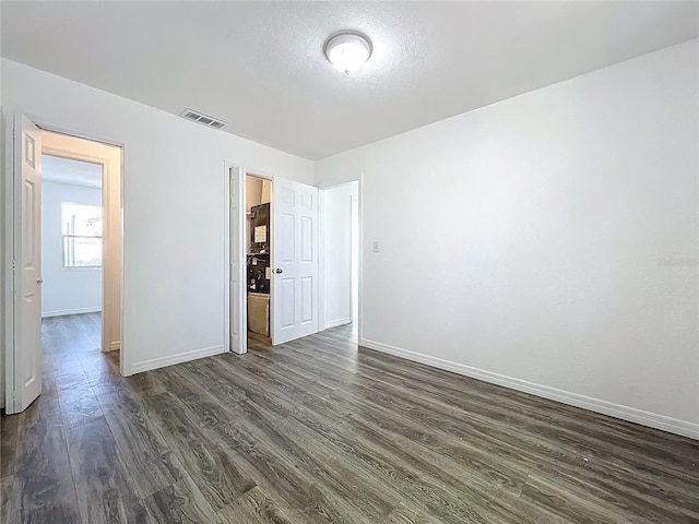 empty room featuring baseboards, visible vents, and dark wood-style flooring