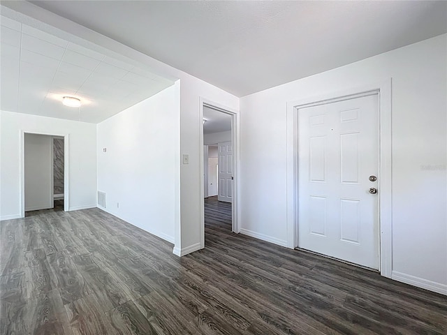 unfurnished room featuring dark wood-type flooring, baseboards, and visible vents