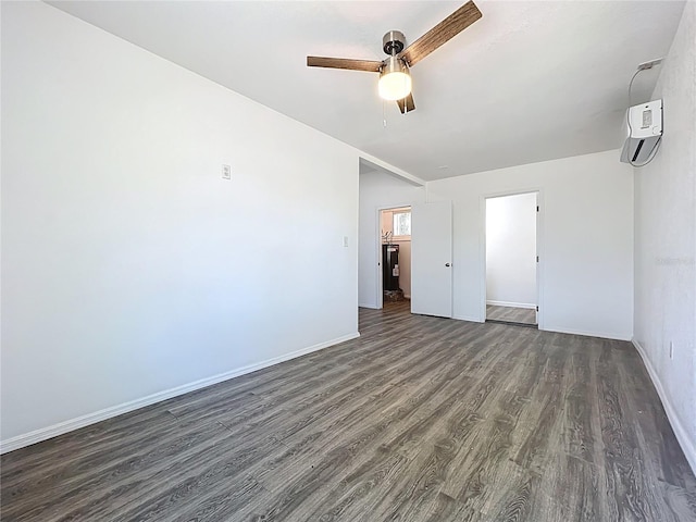 interior space with ceiling fan, an AC wall unit, baseboards, and dark wood-style flooring