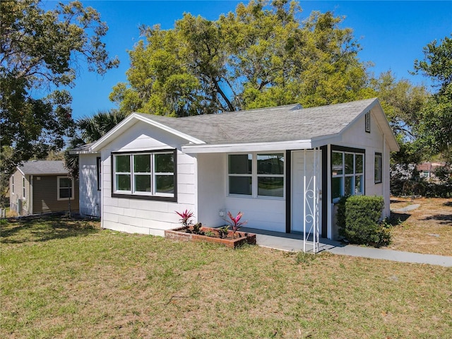 ranch-style home featuring a front yard and a shingled roof