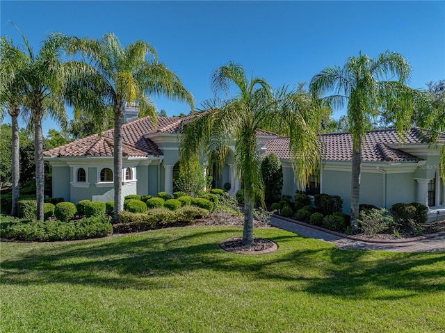 mediterranean / spanish-style home with a front lawn, stucco siding, and a tiled roof